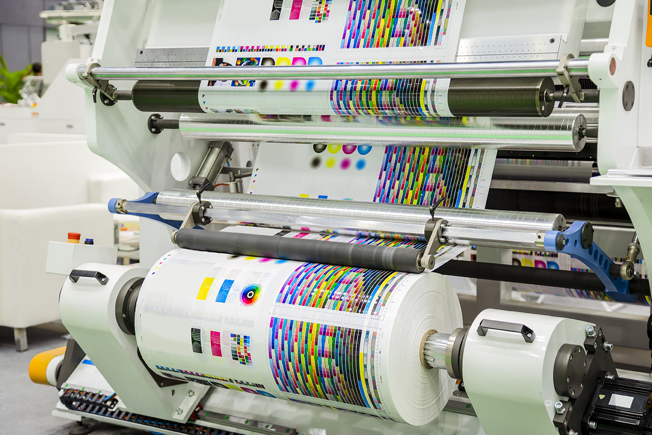 Large offset printing press or magazine running a long roll off paper in production line of industrial printer machine.